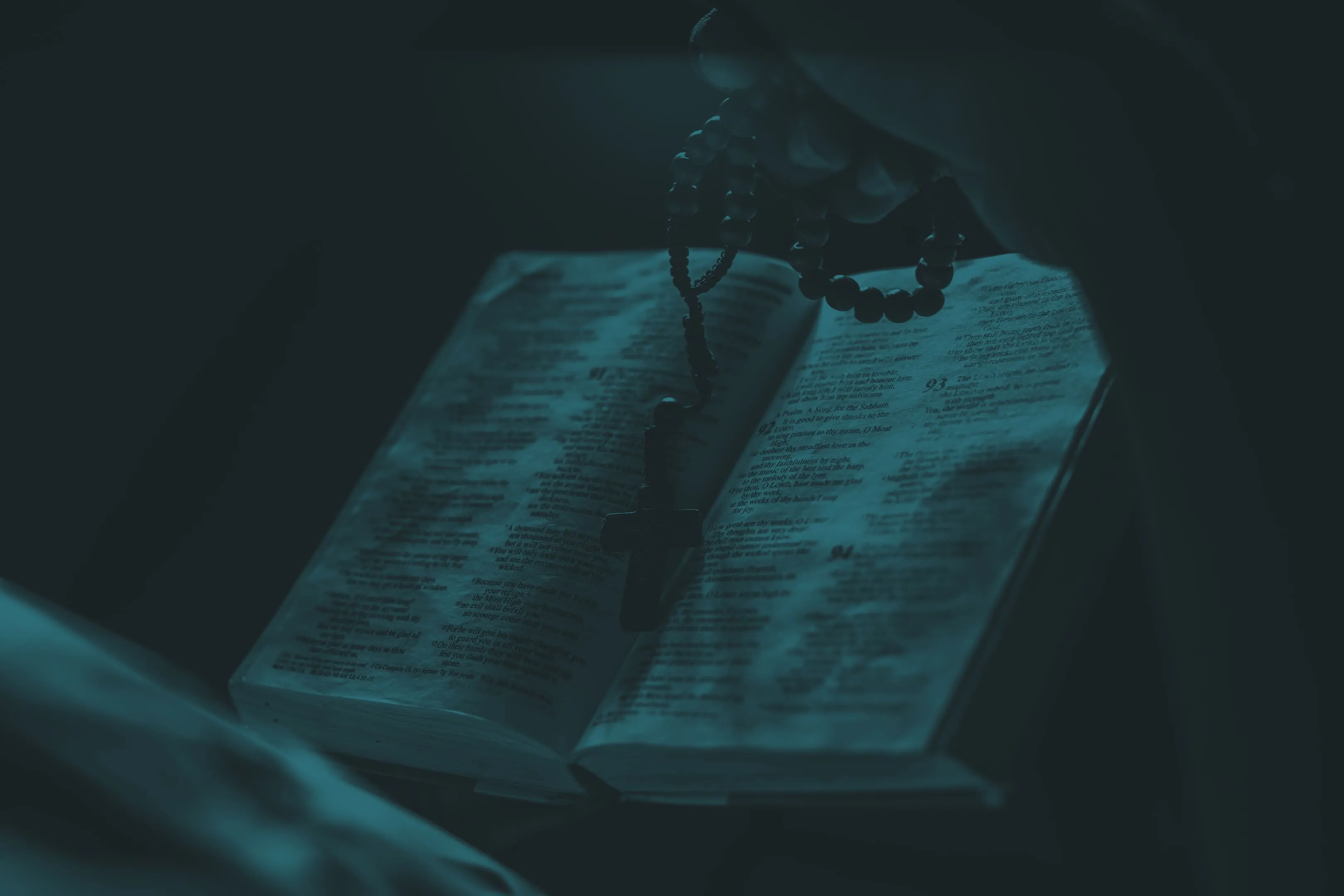 Un rosario de madera y un crucifijo sobre una Biblia abierta